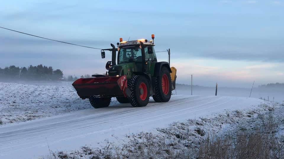 Traktor som kjører på vinterføre
